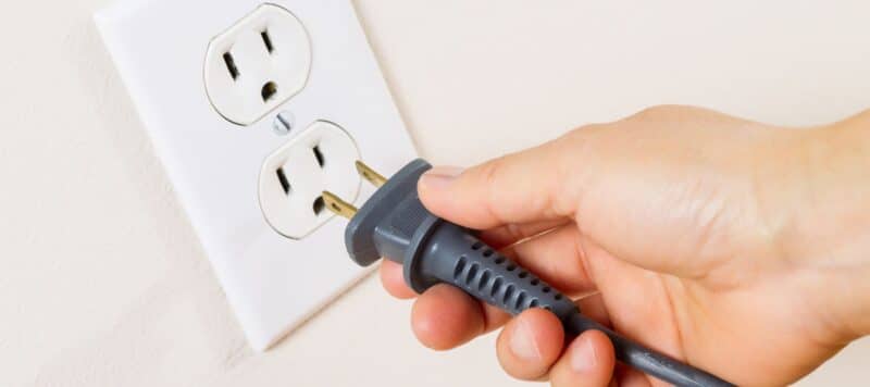 closeup of a hand holding a plug going towards an outlet to plug it in